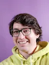 Tyler in a neon yellow sweatshirt and a purple background.
